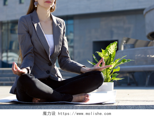 一位年轻的女商人坐在地上练瑜伽打坐的女商人